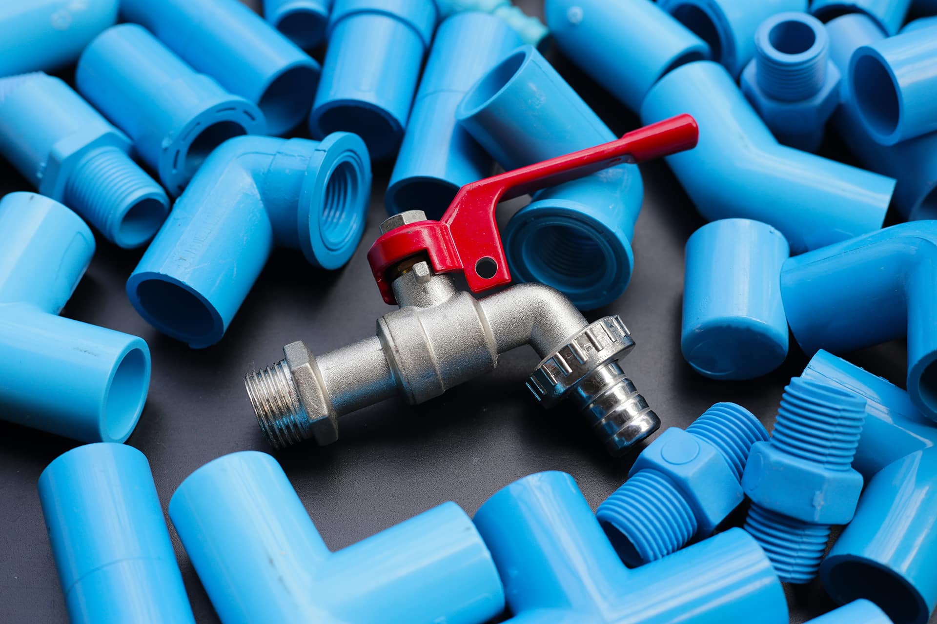 Plumbing tools: red tap and blue PVC fittings.