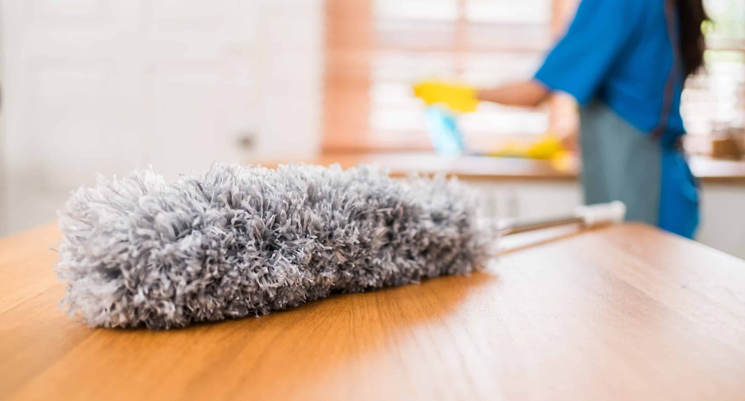 Gray duster on a wooden table, cleaning background.