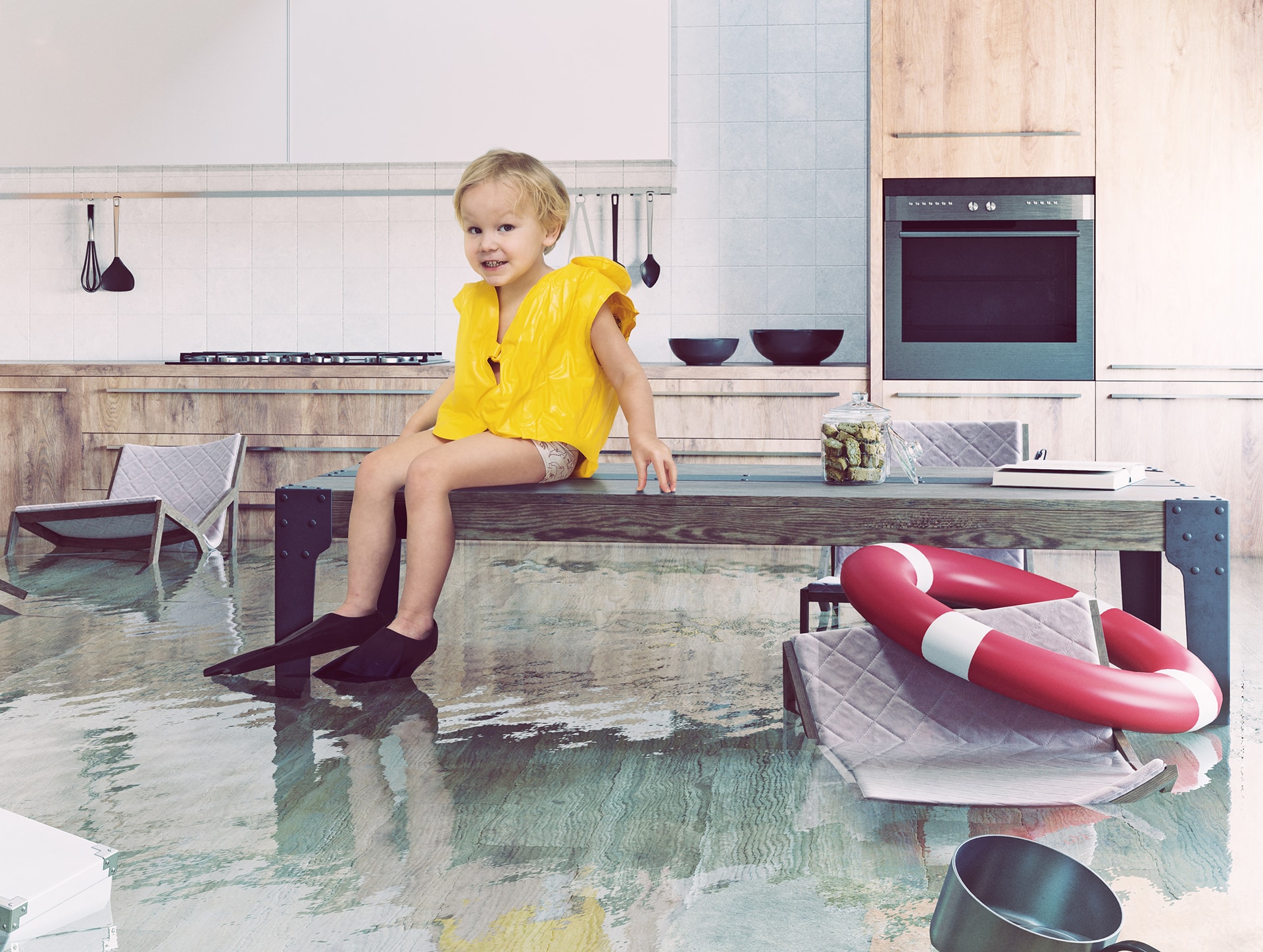 Child in flooded kitchen wearing life jacket and flippers.