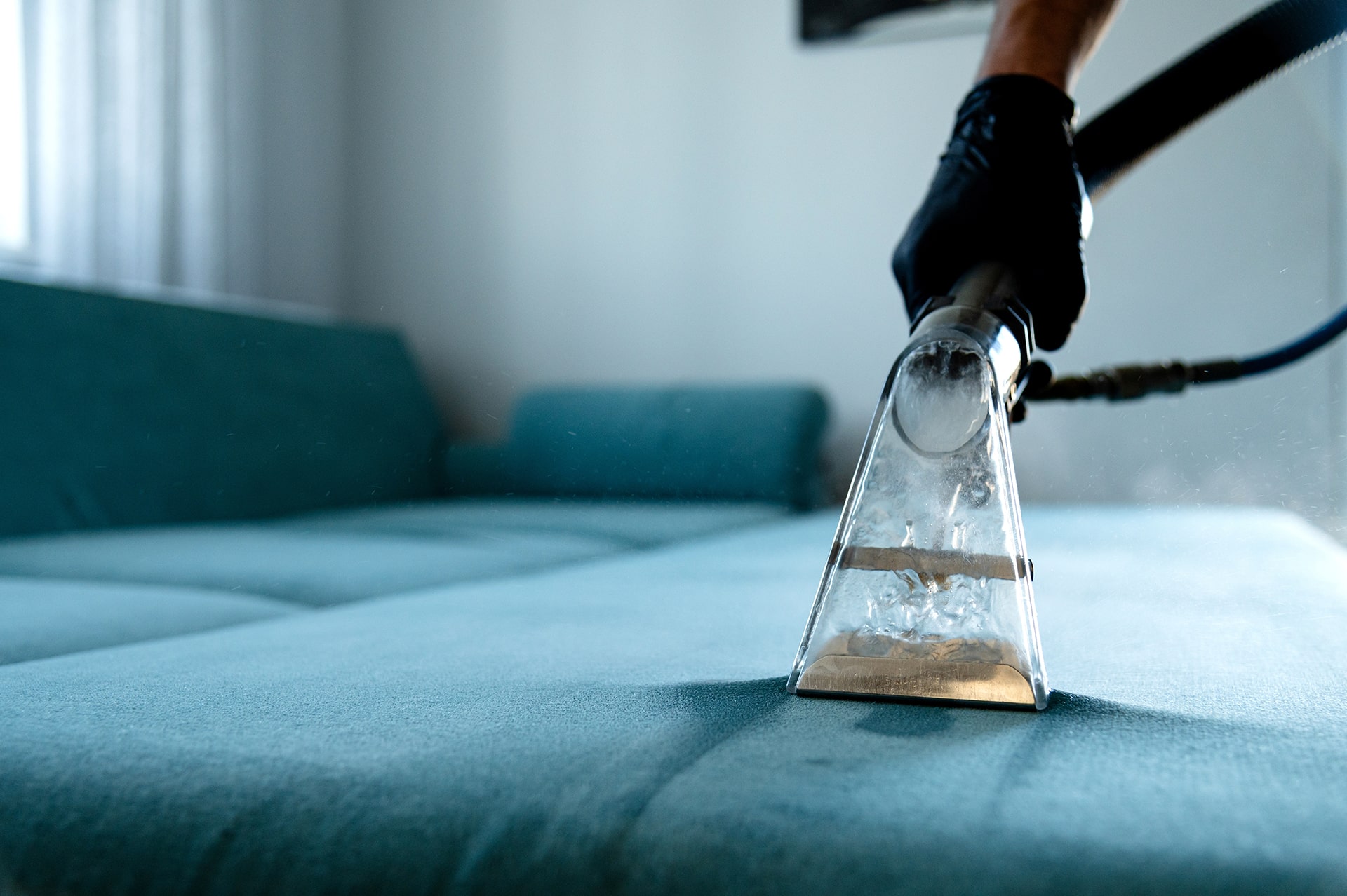 Vacuum cleaning a blue sofa for dirt removal.