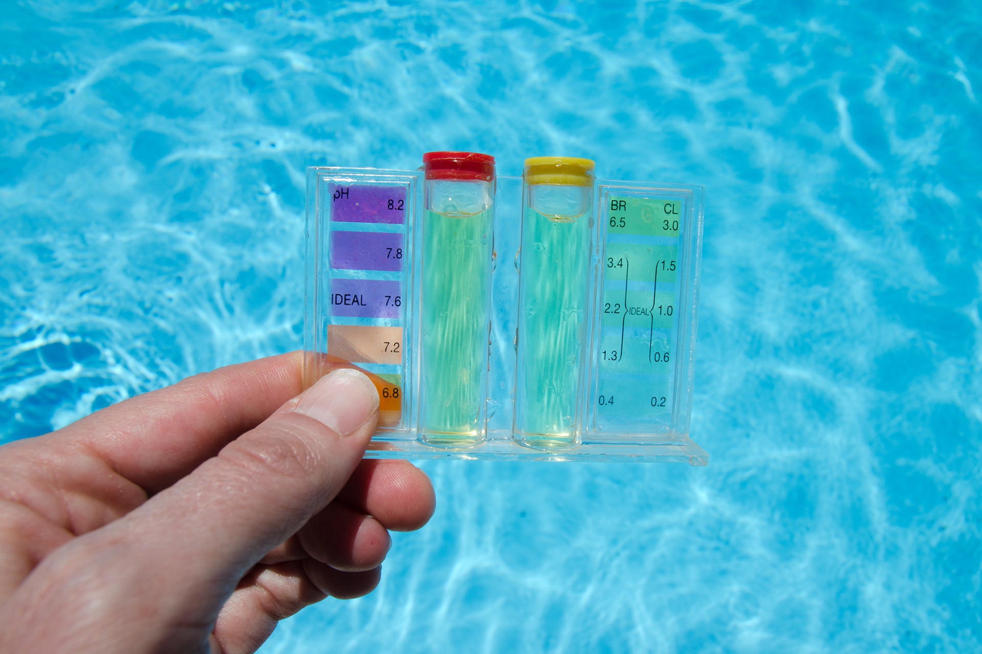 Hand holding pool water test kit.