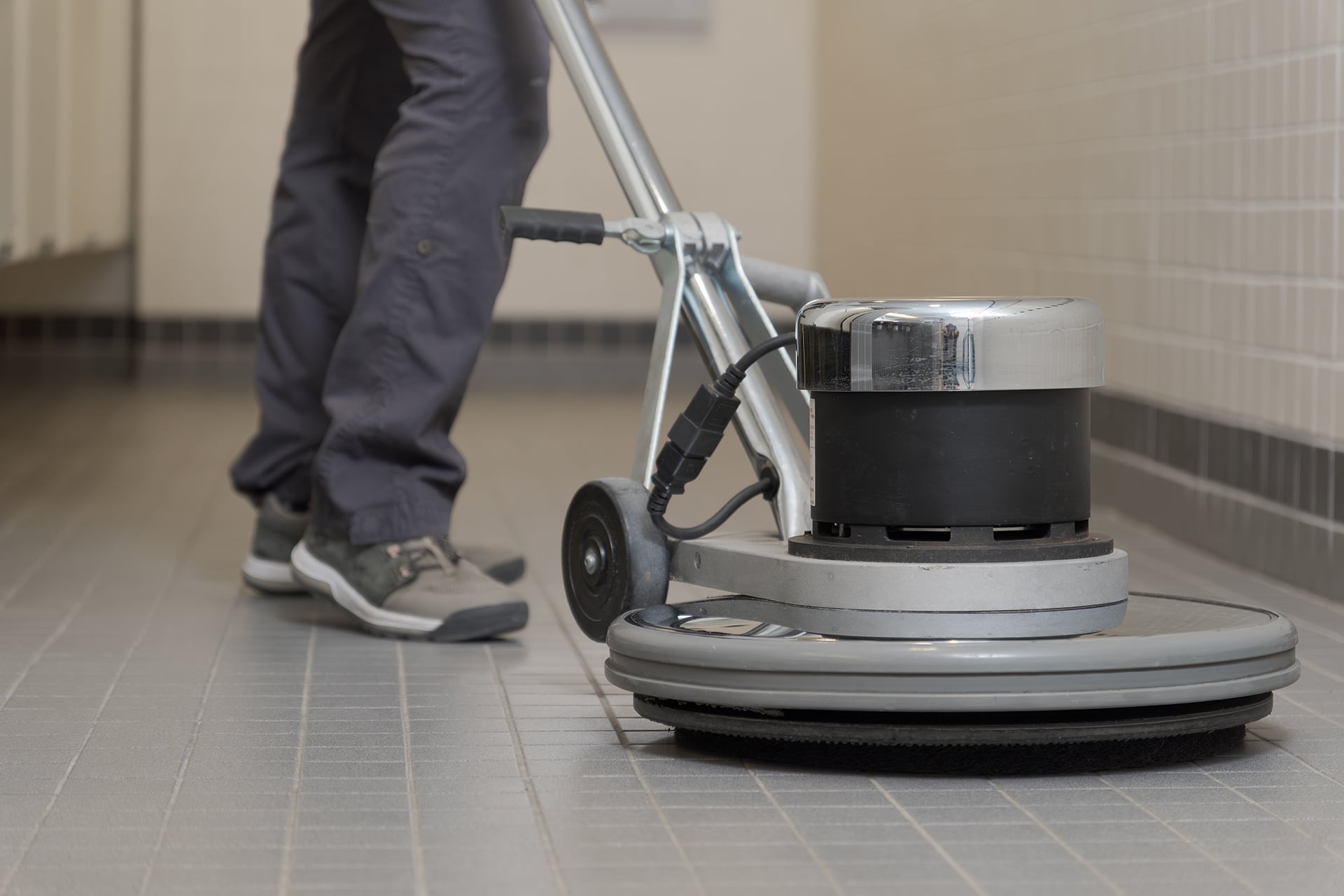 Person cleaning floor with machine polisher.