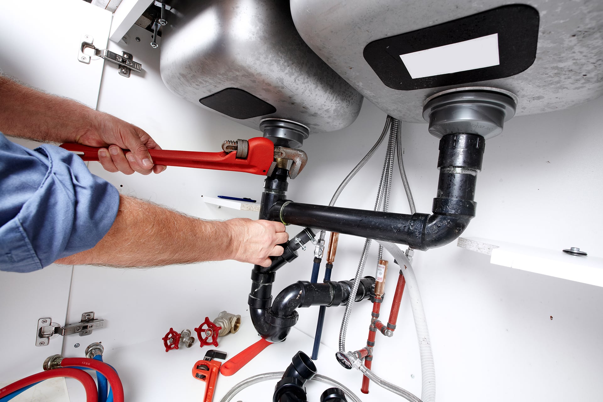 Plumber using wrench on kitchen sink pipes