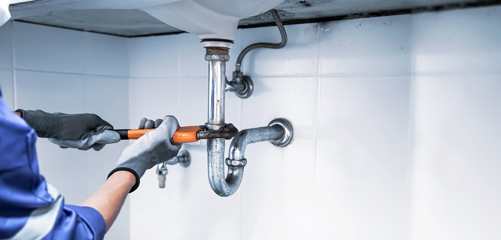 Plumber fixing sink pipes with wrench