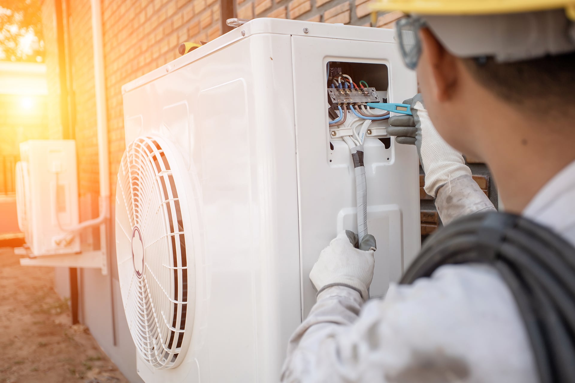 Technician repairing air conditioning unit outdoors.