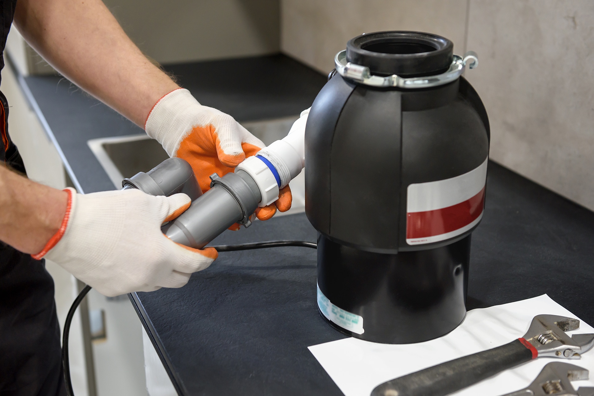 Person installing kitchen garbage disposal system.