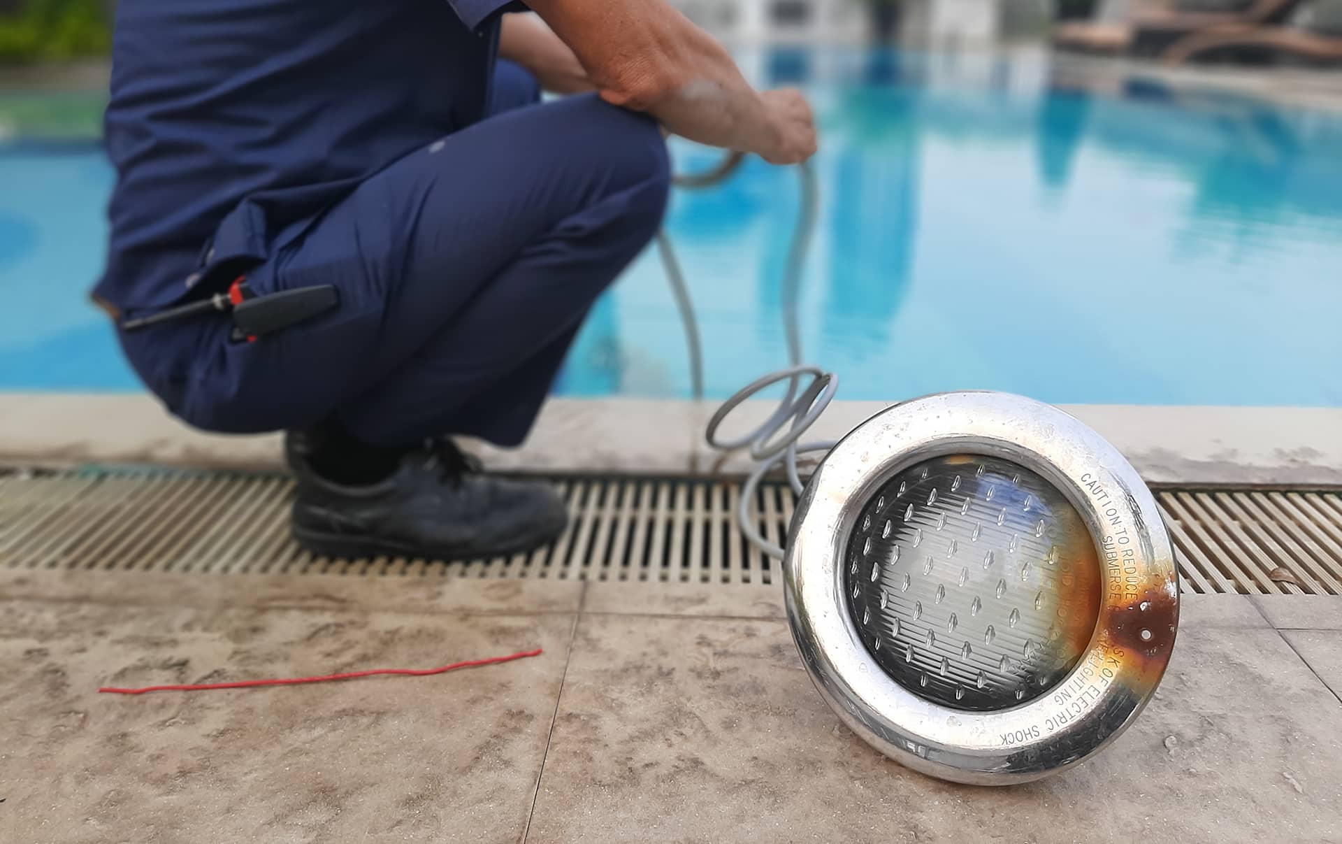 Technician maintaining swimming pool with underwater light.