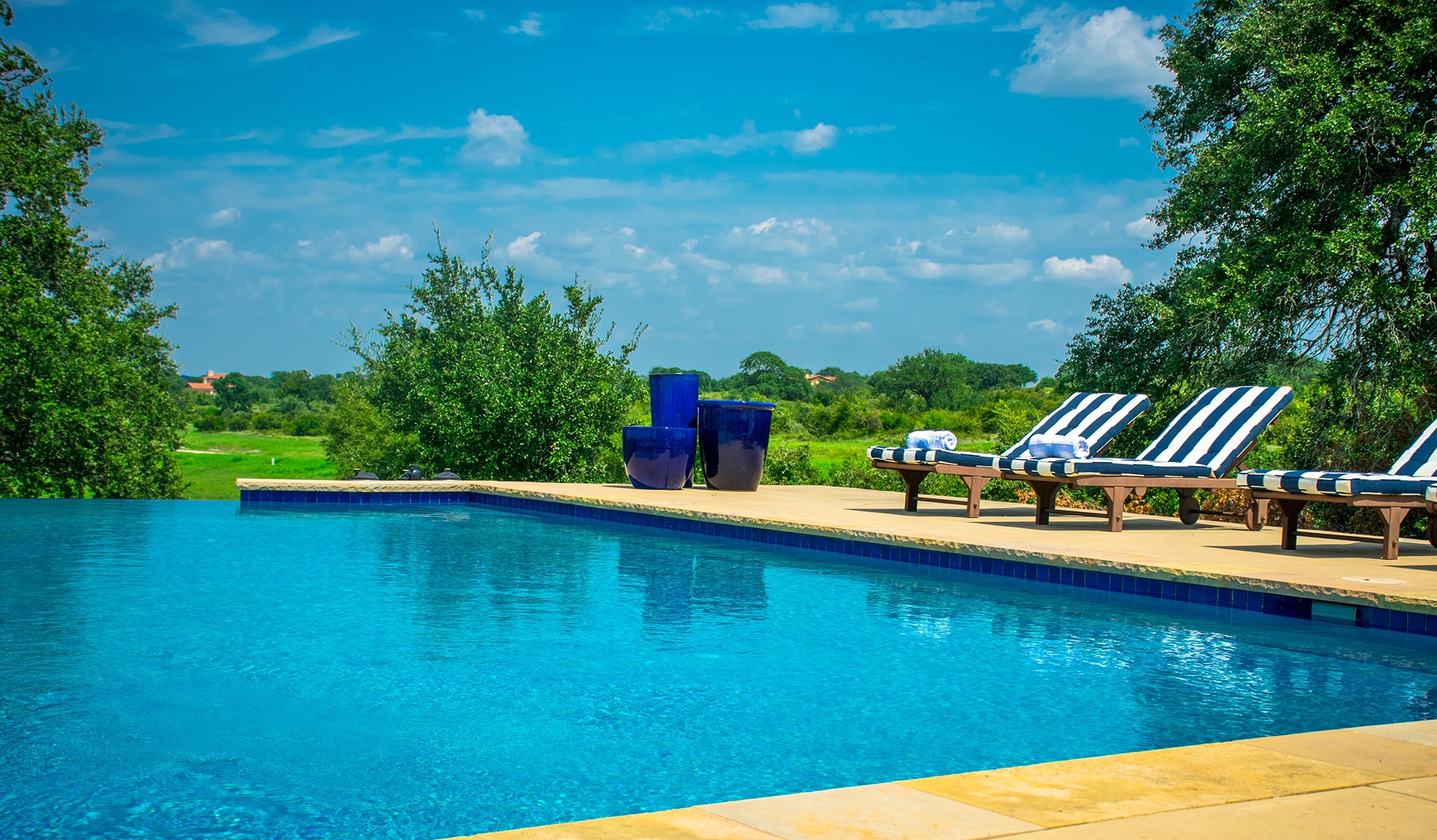 Outdoor pool with lounge chairs and green landscape