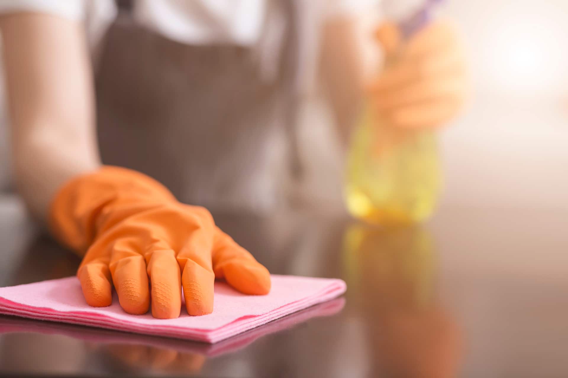 Person cleaning surface with spray and cloth