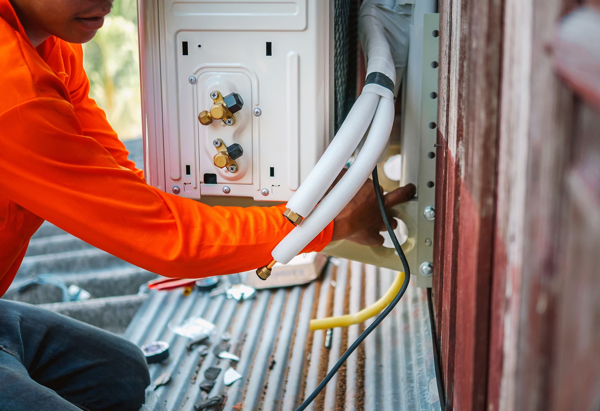 Technician installing air conditioning unit pipes.