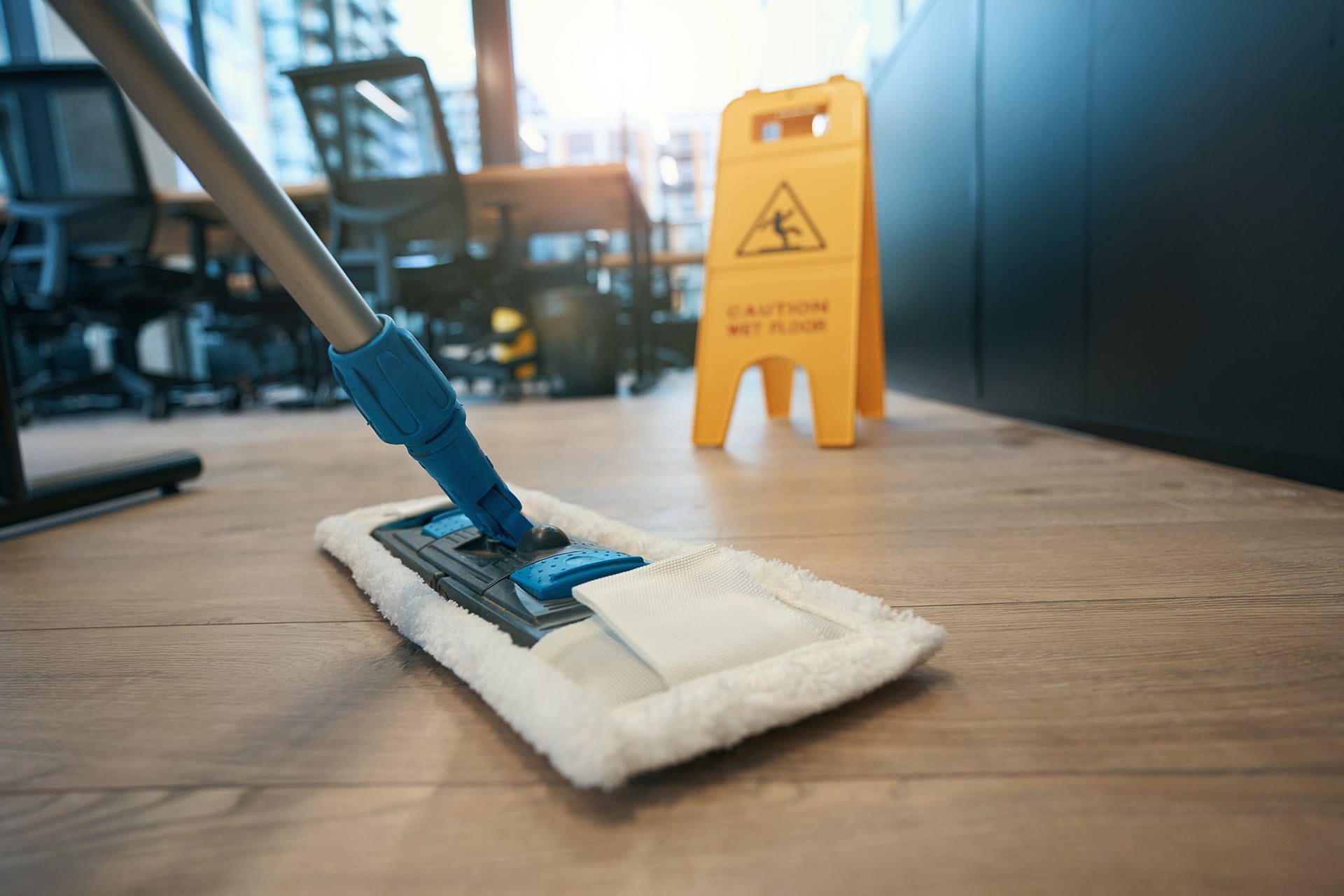 Wet floor caution sign and mop in office.
