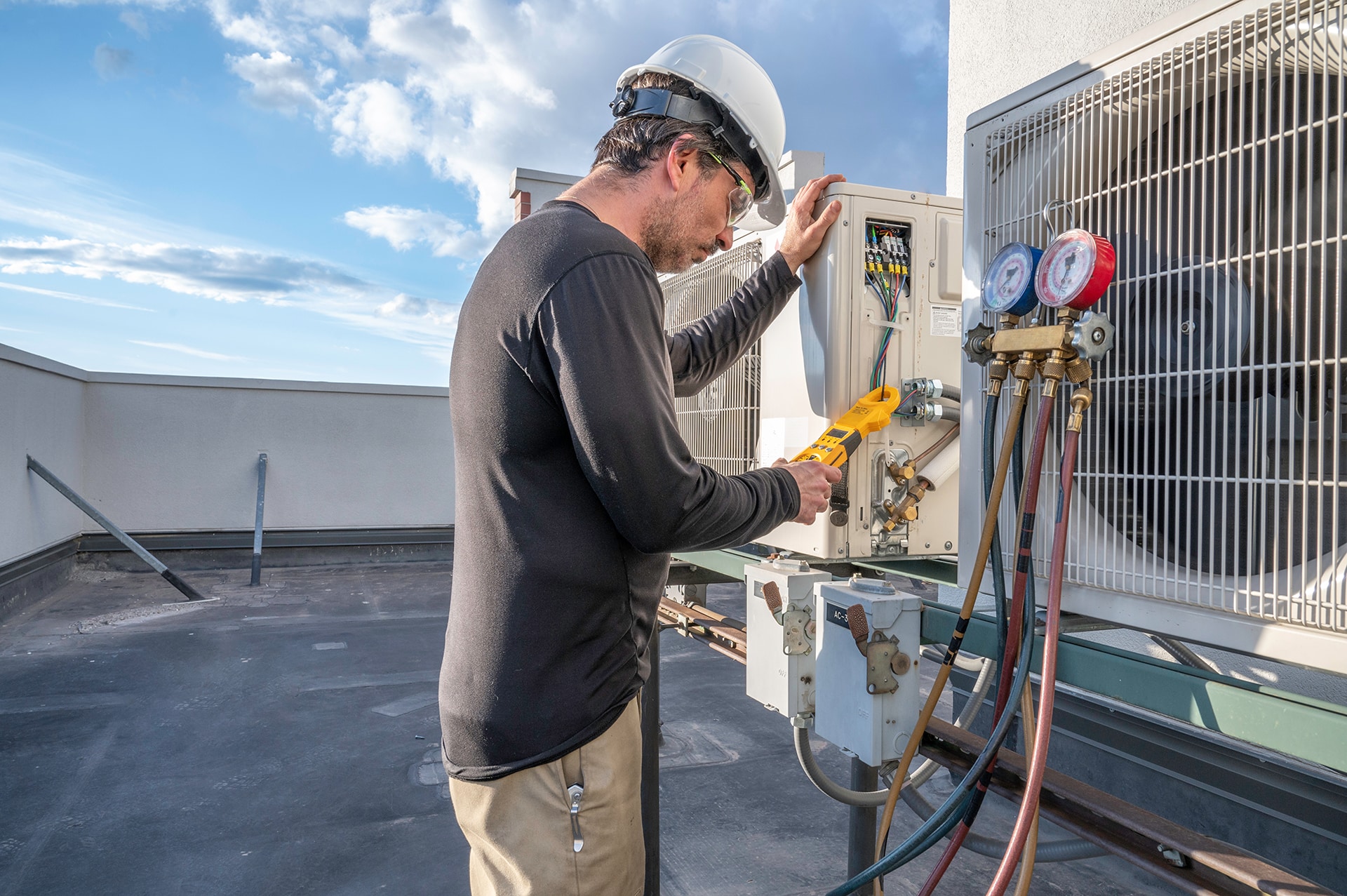 Technician servicing rooftop HVAC unit outdoors.