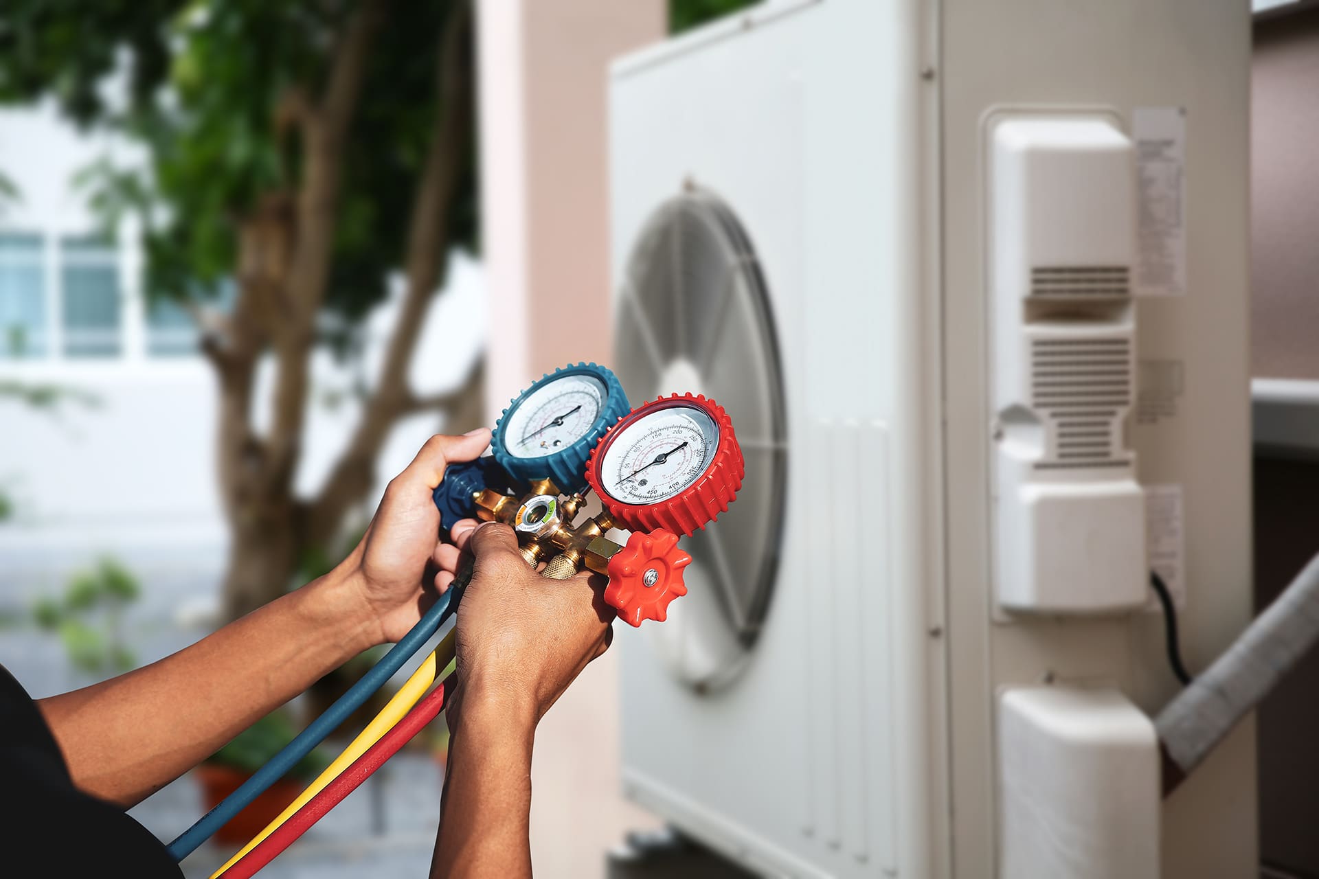 Technician using HVAC pressure gauges on air conditioner.