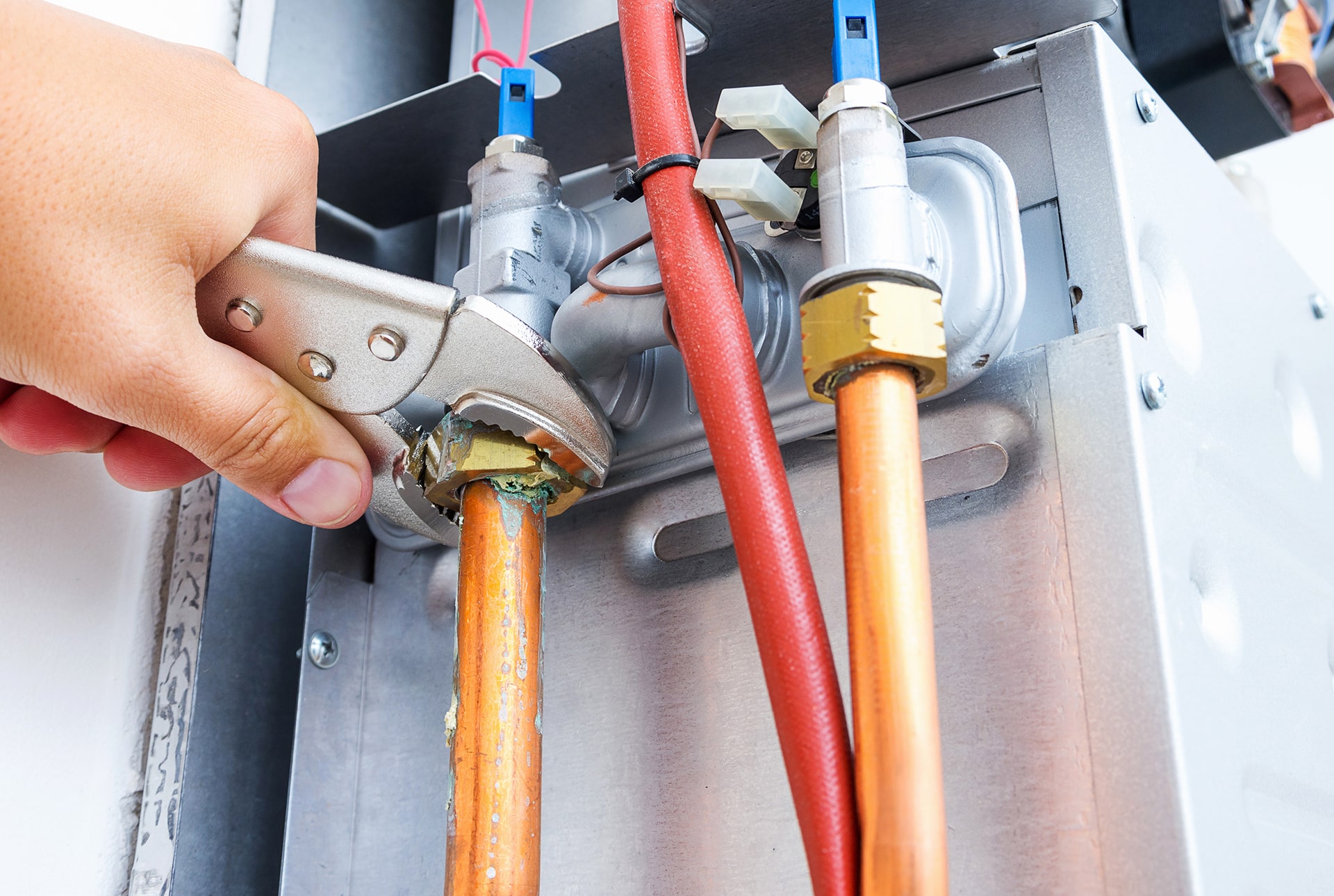 Plumber fixing copper pipes with wrench.