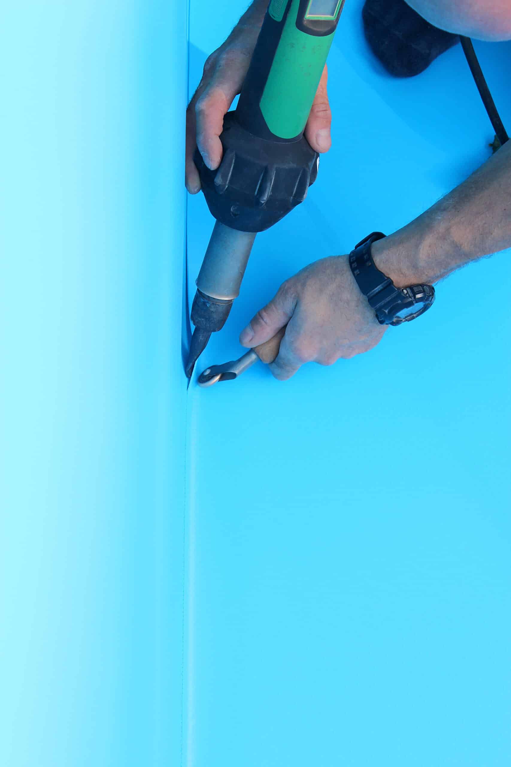 Installing a swimming pool liner with tools.