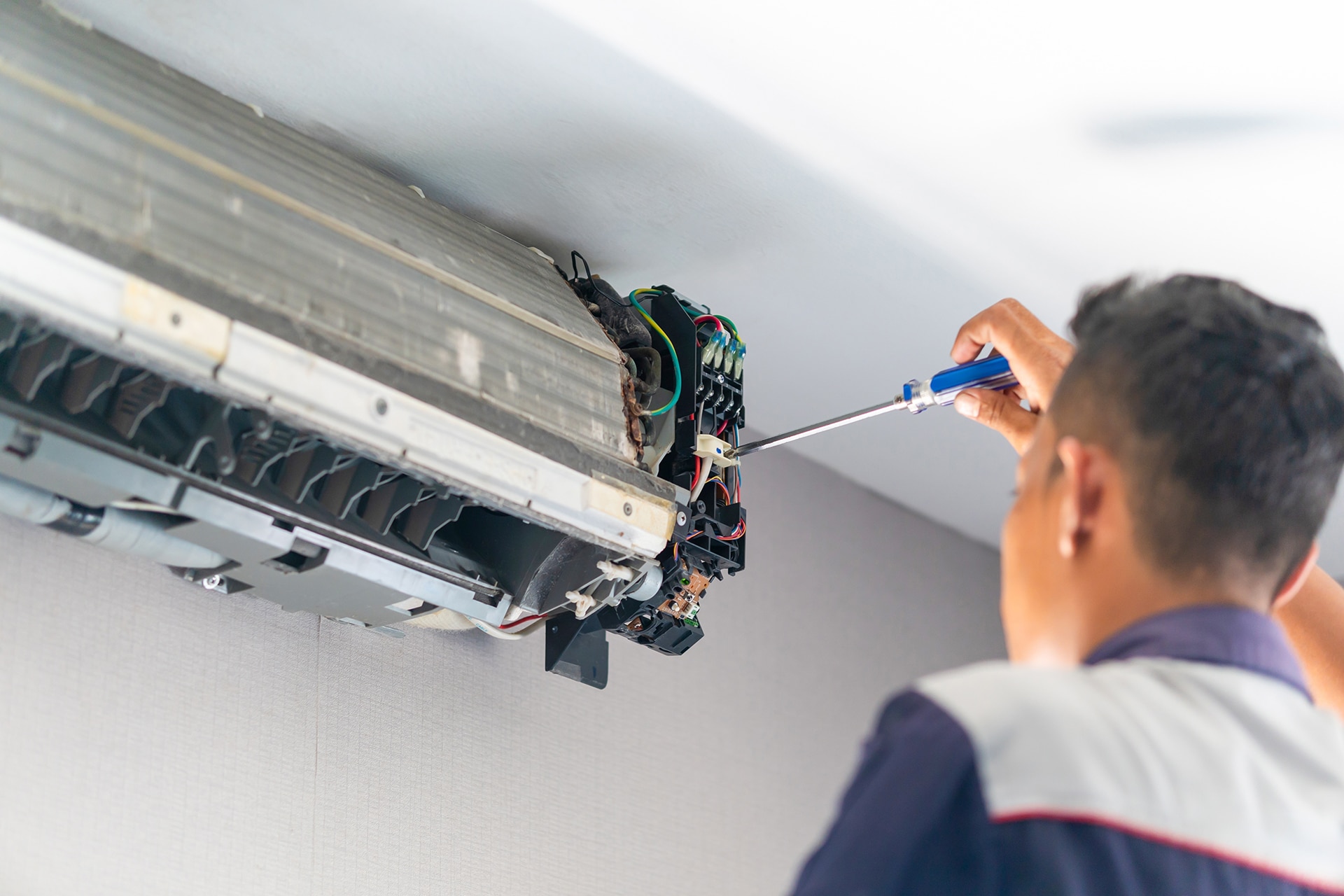 Technician repairing air conditioning unit with screwdriver