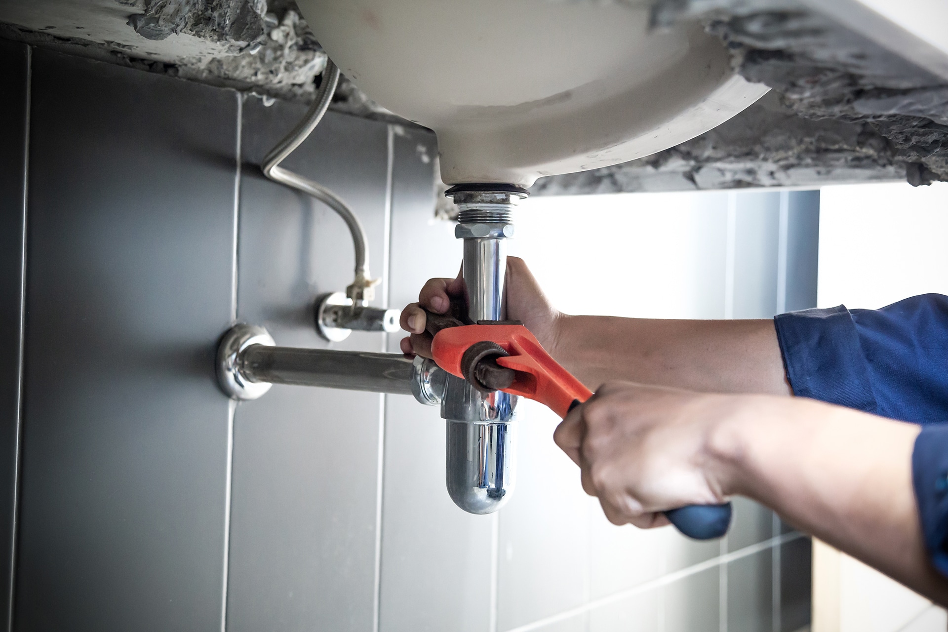 Plumber fixing sink pipe with wrench