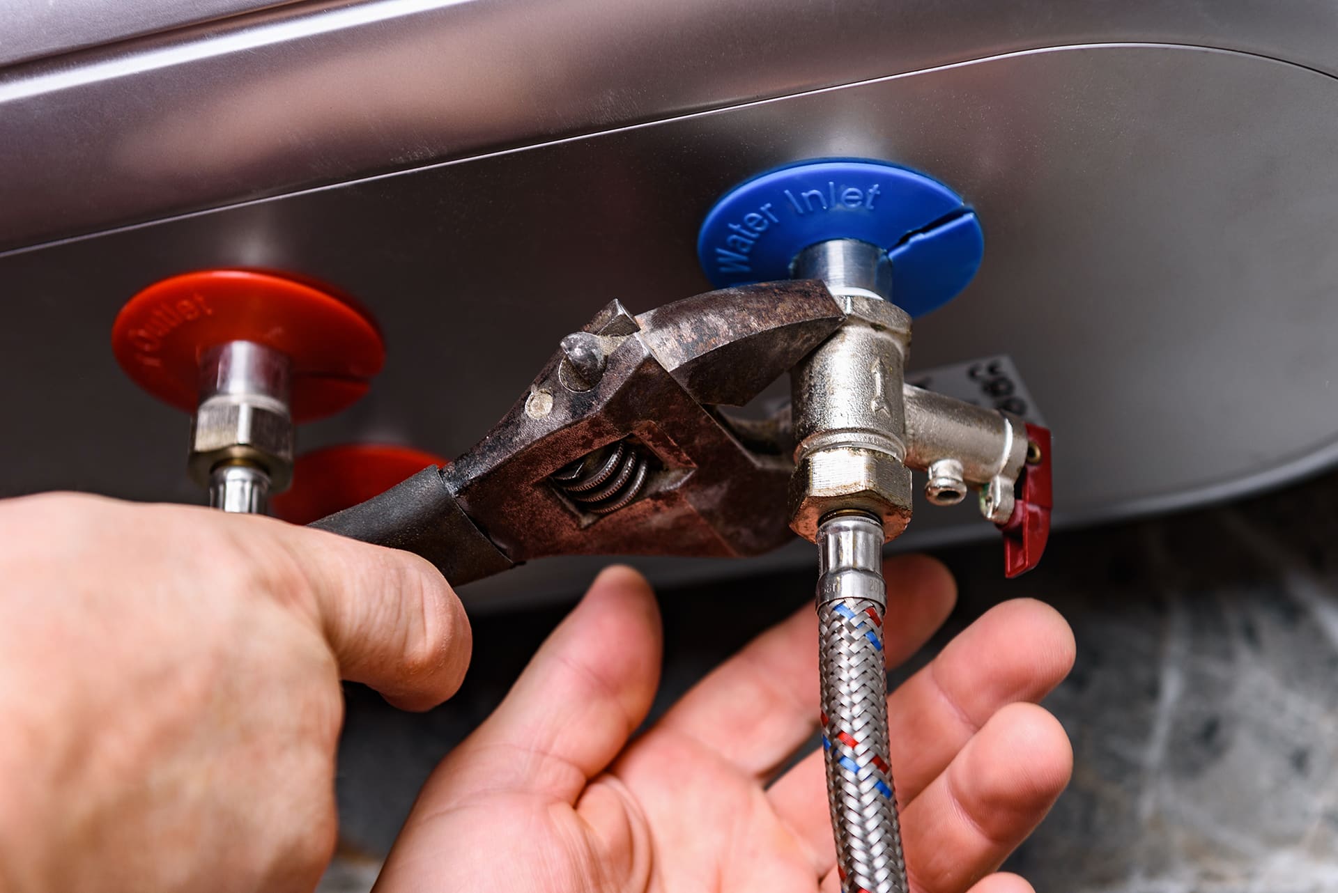 Plumber tightening water heater valve with wrench.