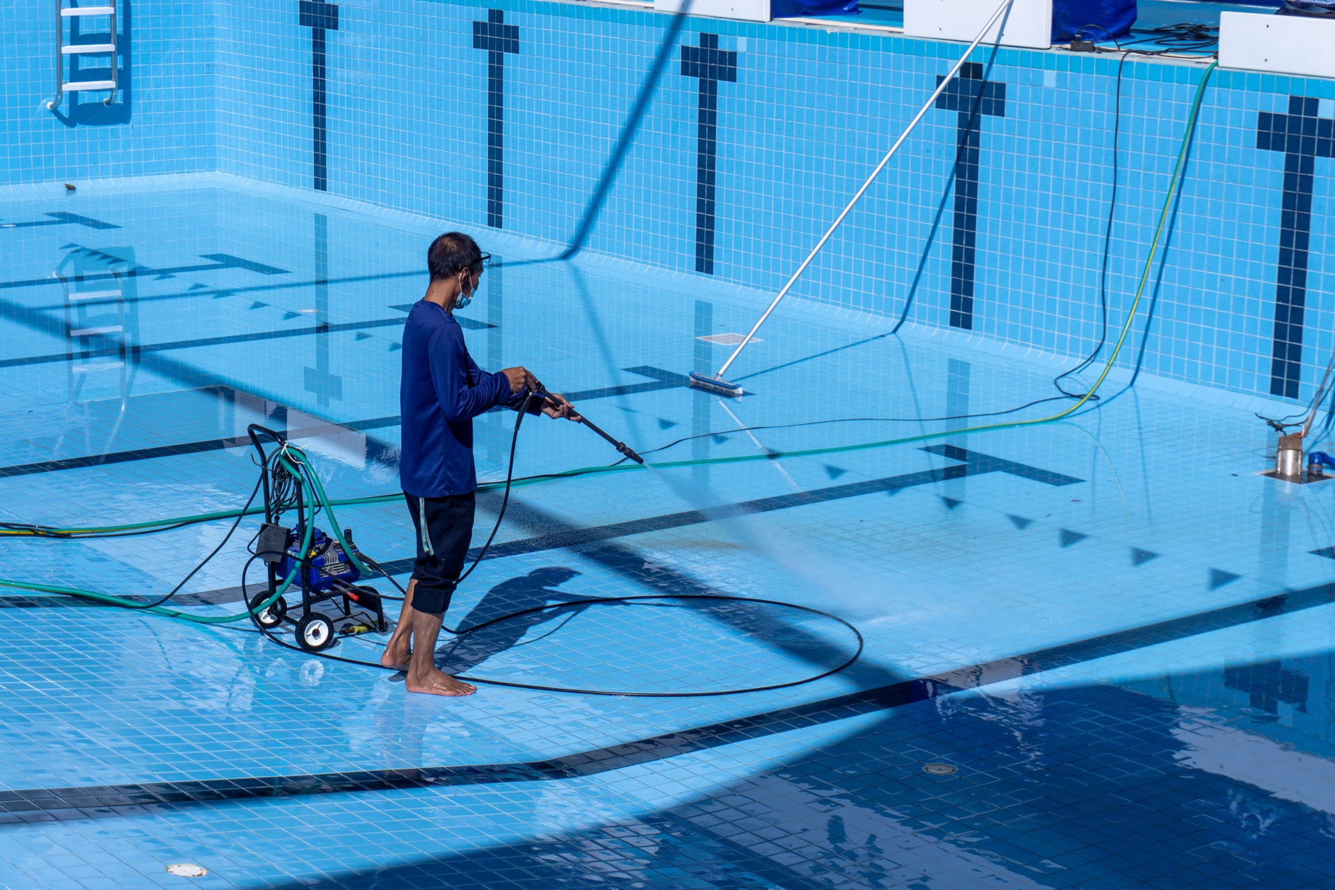 Man pressure washing empty swimming pool