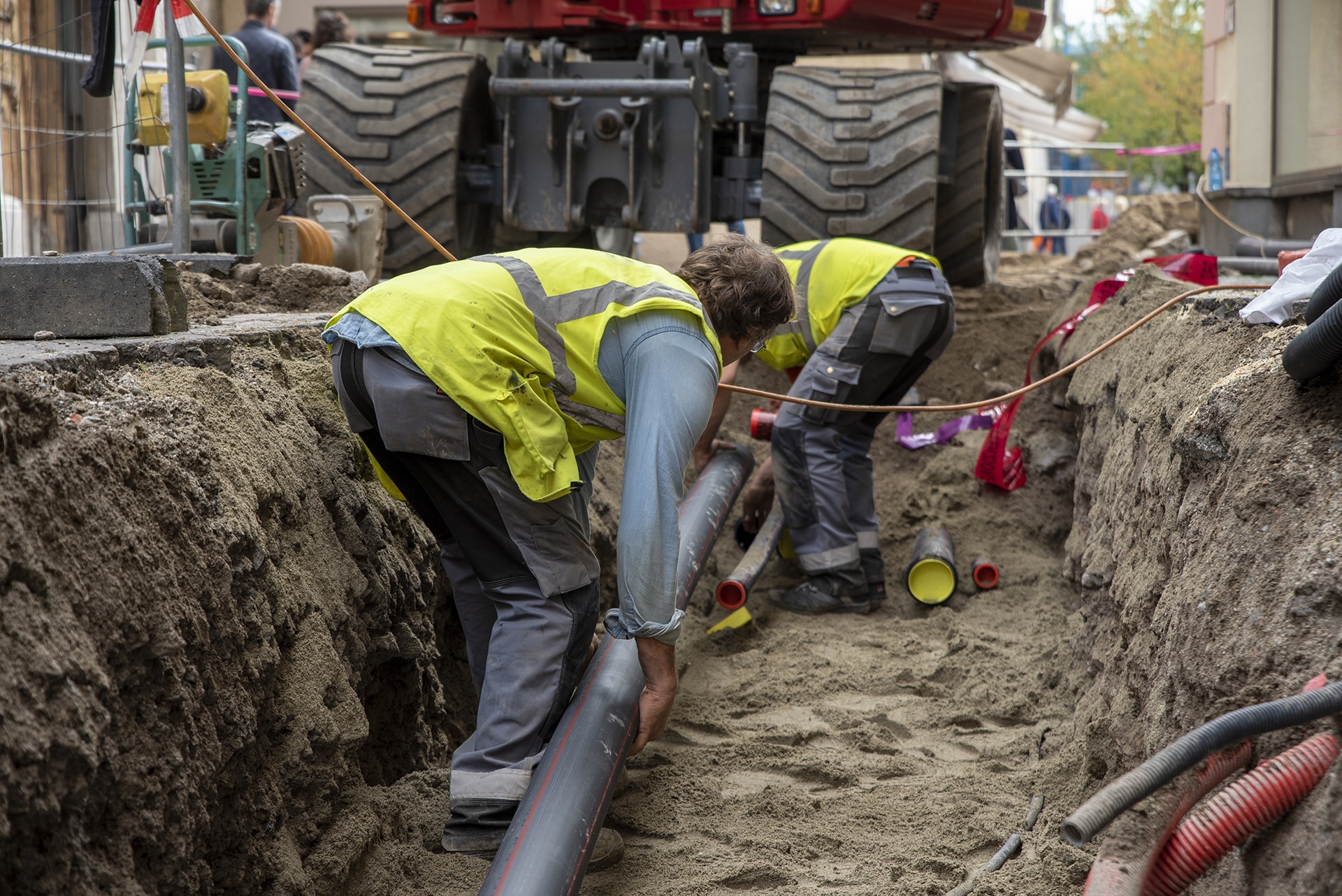 Workers installing pipes in construction trench