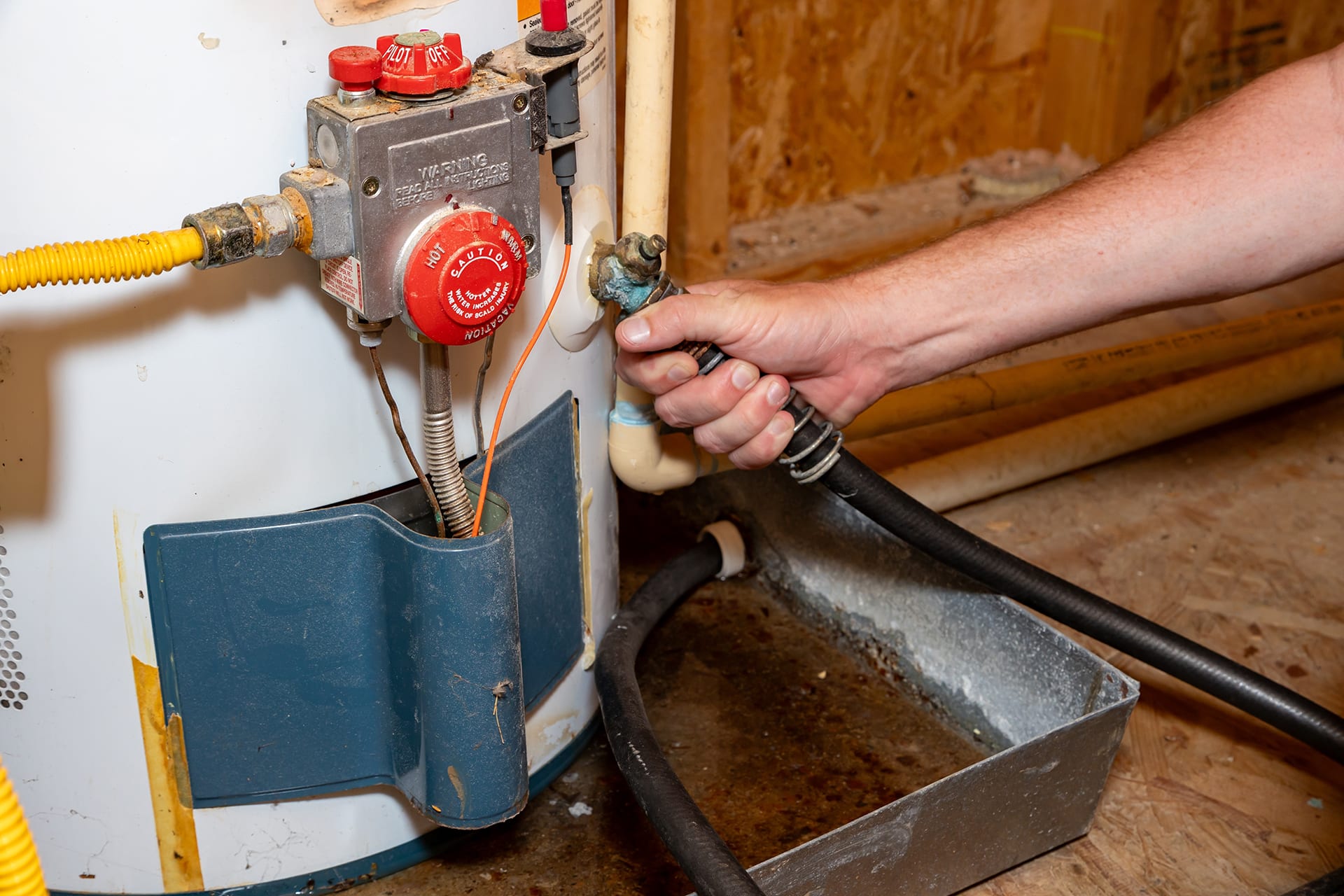Hand adjusting water heater control valve indoors.