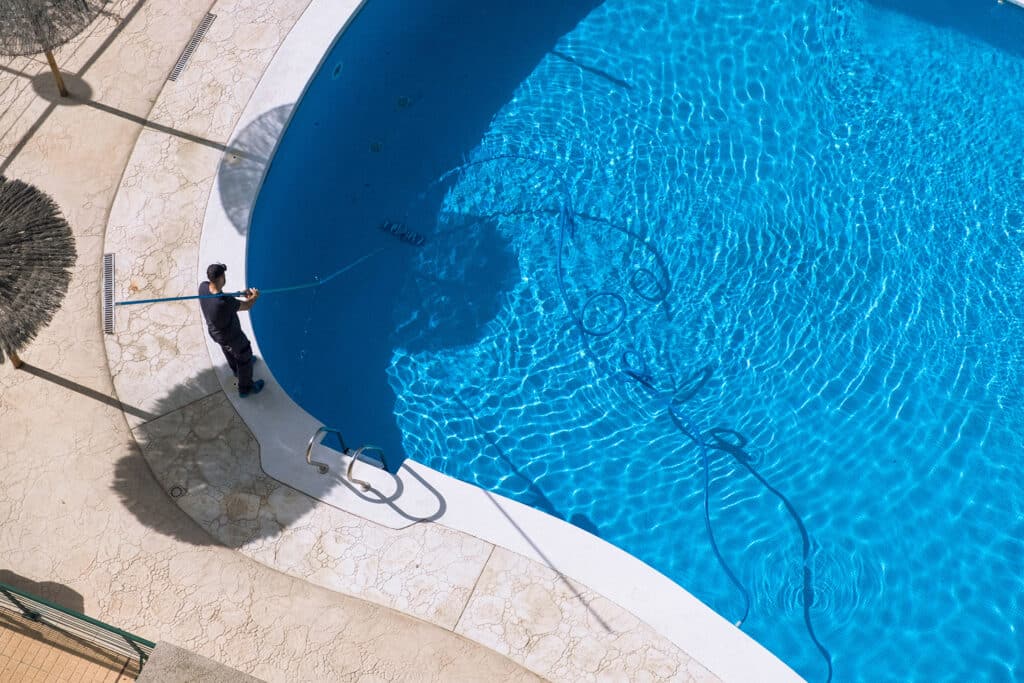 Person cleaning swimming pool with skimmer